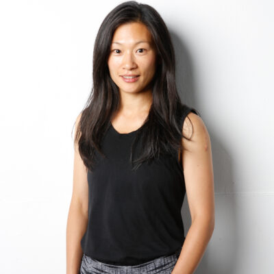 Pei-Ling wears a black tank top and black and white patterned pants. She stands with both hands in the pants pockets, black long hair down.